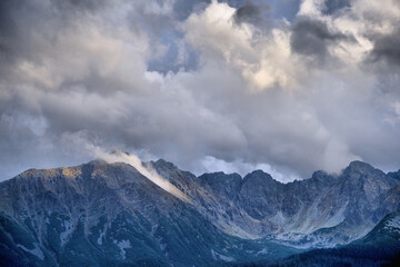 Panorama Tatr z gęstym świerkowym lasem i majestatycznymi szczytami w chmurach