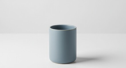 Solid blue ceramic tumbler rests on a white surface against a light background