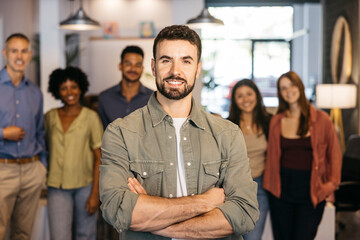 Confident business leader proudly standing with diverse office team