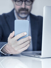 Mobile Communication: A Modern Professional Engaged with a Smartphone While Working on a Laptop