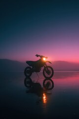 Obraz premium Motorcycle against a vibrant sunset on a tranquil beach