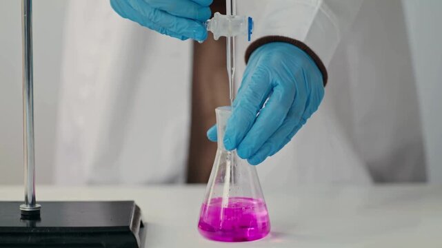 Close-up 4K Ultra HD footage of a scientist releasing liquid from a burette into a flask in a laboratory, showing precise measurement, fluid motion, and detailed chemical experiment process.