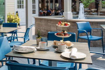 Afternoon tea setup at a modern outdoor cafe with a fountain and vibrant seating in a sunny atmosphere