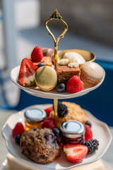 Delicious dessert platter with assorted pastries, fresh fruits, and jams served outdoors on a sunny day