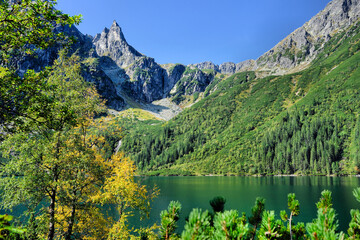 Tatry Wysokie, szczyt Mnich nad Morskim Okiem, spokojne górskie jezioro i jesienna roślinność © Przemysaw