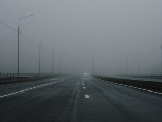 Fototapeta premium Dangerous dense fog on the highway. Poor visibility. Cars in the fog.