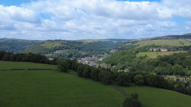 Aerial view of the hebden bridge in summer showing the town at the bottom of the colden and calder valleys surrounded by woodland and fields with the village of Heptonstall visible in the distance