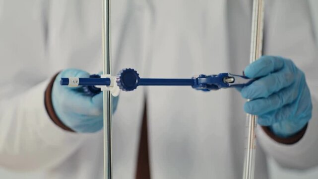 Close-up 4K Ultra HD footage of a scientist adjusting a burette clamp in a chemistry laboratory, showing precise experimental setup, glassware handling, and scientific procedure.
