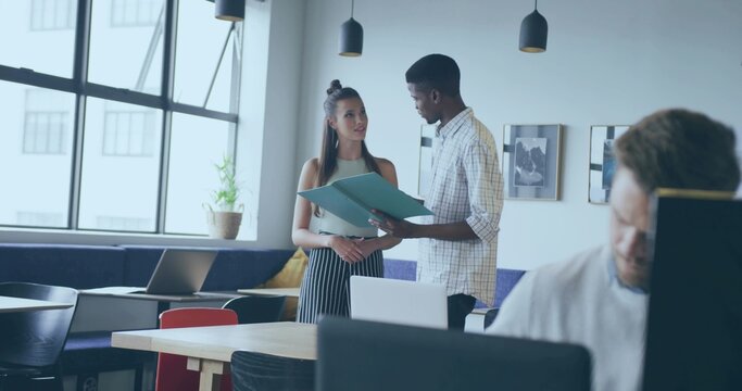 Discussing turquoise folder, African American man and White teen at open-plan office with laptop - Powered by Adobe