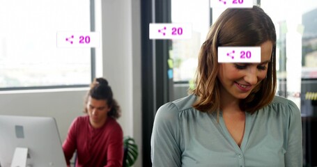 Obraz premium Smiling woman colleague standing by partition in office with monitor and share icons showing 20