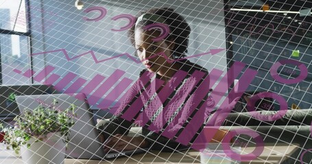 Analyzing mid-adult woman reviewing charts on laptop at desk in office, with plant, sticky notes