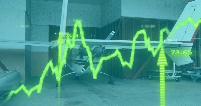 Displaying white propeller airplane resting inside hangar bay, with green digital graph overlay - Powered by Adobe