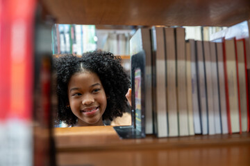 African American young student girl finding book on the bookshelf in school library. Learning,...