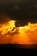 Fototapeta premium Fiery orange sunset sky with dramatic clouds and glowing sunlight