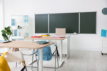Green chalkboard and stylish furniture in classroom. Mockup for design
