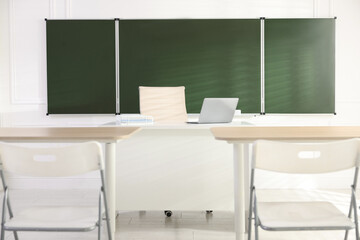 Green chalkboard and stylish furniture in classroom. Mockup for design