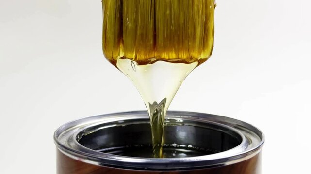 Close-up 4K Ultra HD footage of a paint brush dripping with lacquer as it is pulled from a bucket, showing glossy liquid texture, smooth coating, and detailed artistic process.