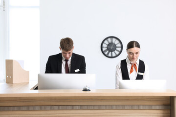 Receptionist and hostess working at reception desk in hotel