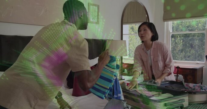 couple placing open suitcase in bedroom and packing for travel exchanging towel and sorting clothes
