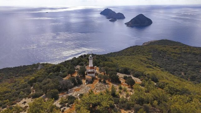 Gelidonya Lighthouse stands on a green hill, with multiple rocky islands in the serene blue sea. Kumluca, Antalya - Turkey