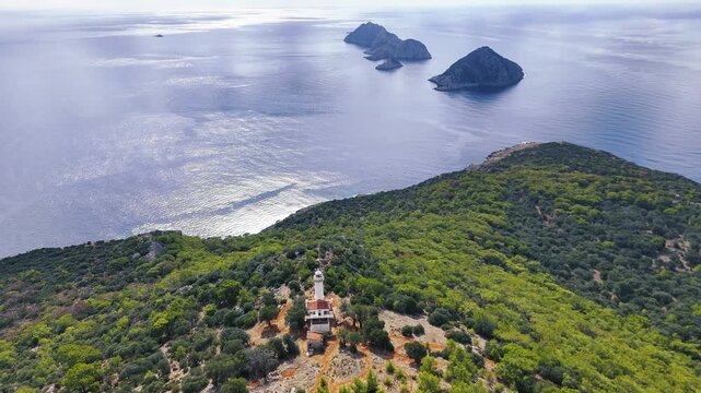 Gelidonya Lighthouse stands on a green hill, with multiple rocky islands in the serene blue sea. Kumluca, Antalya - Turkey