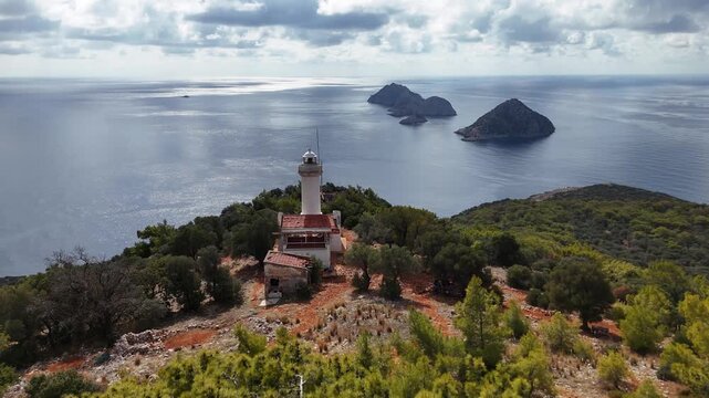 Gelidonya Lighthouse stands on a green hill, with multiple rocky islands in the serene blue sea. Kumluca, Antalya - Turkey