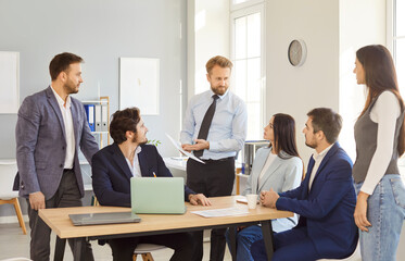 Male confident leader talking to diverse business team during meeting in modern office interior,...