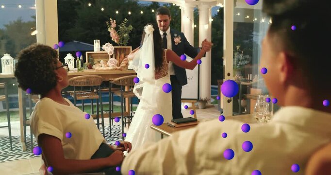 Groom offering hand to bride and starting first dance celebrating marriage under string lights