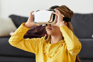 Young girl exploring new worlds with virtual reality at home in her cozy casual outfit