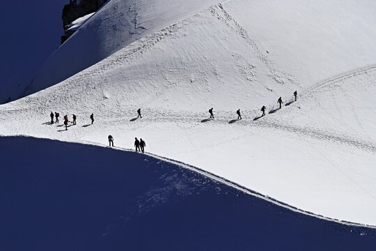 A group of mountaineers runs across a snow-covered mountain, Aiguille du Midi, Chamonix-Mont-Blanc, Haute-Savoie, France