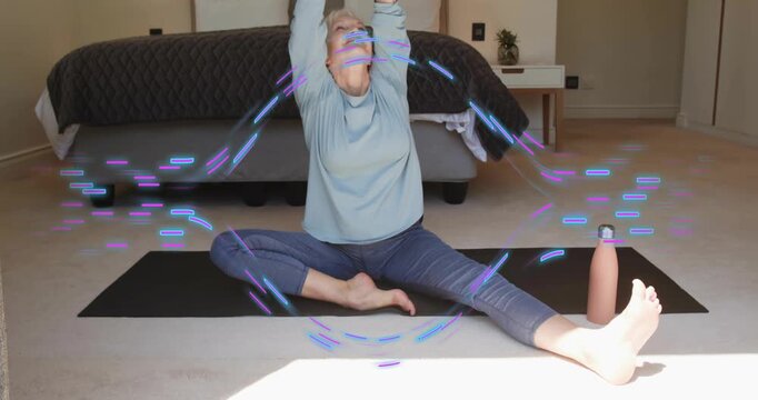 Senior woman lifting right knee to chest on black yoga mat in bedroom, deepening wellness stretch