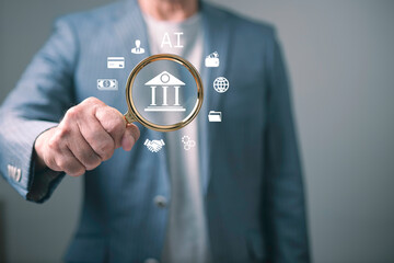 Businessman holding magnifying glass with AI banking icons concept, representing financial...