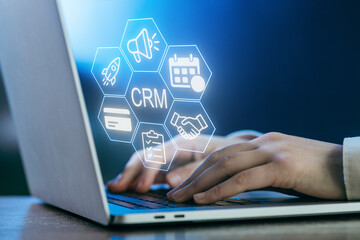 Hands typing on a laptop with digital icons symbolizing customer relationship management in a modern workspace
