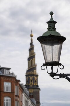 Old street lamp, corkscrew-shaped tower of the Evangelical Lutheran Church of the Saviour, in front of Frelsers Kirke, Christianshavn, Copenhagen, Denmark