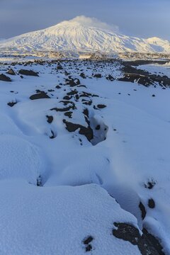 Lava field in front of a volcano, evening light, sun, snow, winter, Arnarstapi, Snaefellsj&ouml;kull, Snaefellsnes, Vesturland, Iceland