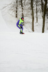Bearded man enjoying snowboarding on a beautiful winter slope surrounded by trees