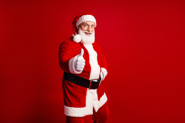 Santa in a red suit gives thumbs up against a bold festive red background perfect for Christmas marketing