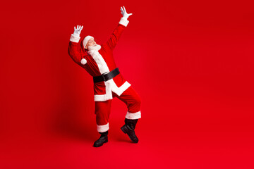 Santa Claus in red suit striking a dynamic pose against a solid red background perfect for Christmas holiday stock photos conveying festive mood