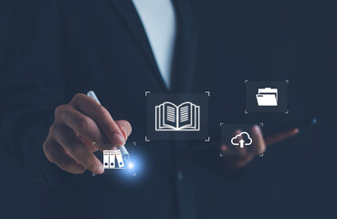 Businessman using digital pen with icons of book, folder, and cloud upload. Concept of e-learning, online education, digital library, knowledge management, cloud data technology for modern business.