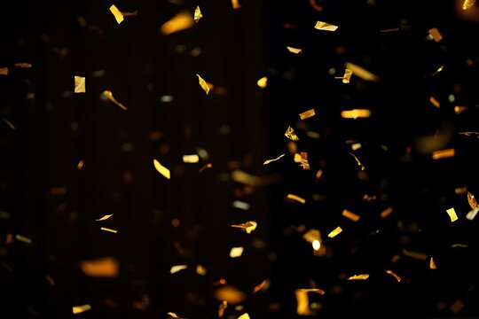 Golden confetti falling on black background celebration and luxury design