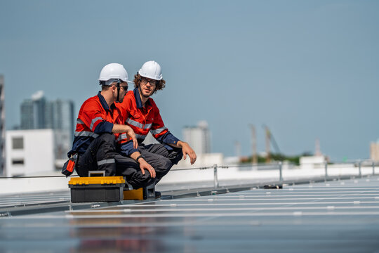 Solar engineer teamwork maintenance energy discussion on rooftop panel under bright sky with hard hat and safety uniform focus on inspection and repair workflow for clean power