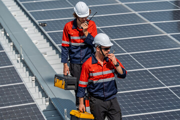 Solar engineer teamwork maintenance energy rooftop technician with helmet tool box radio communication inspection under sunlight on panel field showing focus and safety during routine service