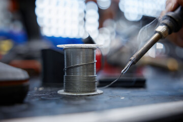 An individual is using a soldering iron to solder a wire together
