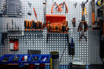 A collection of various tools is hanging on an organized wall