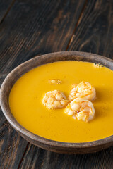 Clay bowl of creamy shrimp bisque served warmly on rustic wooden table