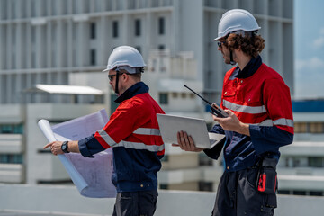 Solar engineer teamwork on rooftop maintenance site ensure safe energy flow under bright sky while reviewing plans and laptop with calm focus and clear communication for reliable power operations