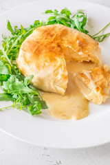 Melted Camembert en Croûte with rosemary garnish and vibrant cranberry sauce accompaniment