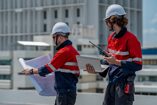Solar engineer teamwork on rooftop maintenance site ensure safe energy flow under bright sky while reviewing plans and laptop with calm focus and clear communication for reliable power operations