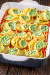 Golden baked lumaconi filled with ricotta and spinach resting in rich tomato sauce