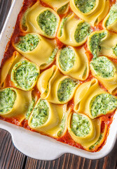 Golden baked lumaconi filled with ricotta and spinach resting in rich tomato sauce